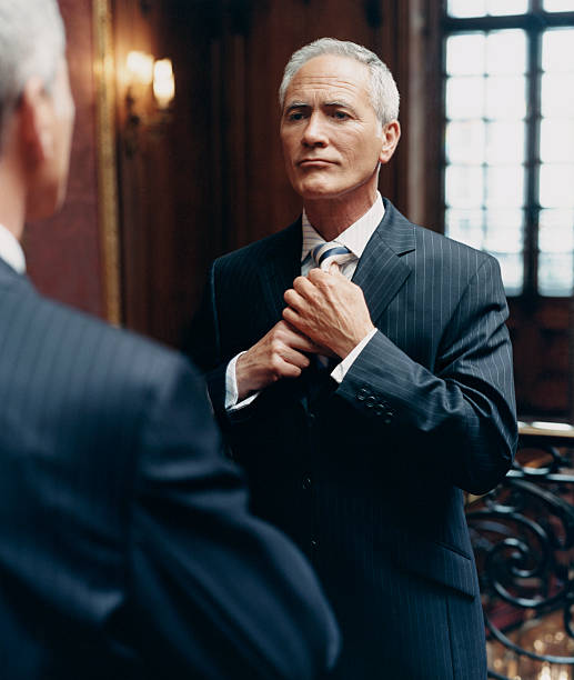CEO adjusting his suit while seeing himself in a mirror